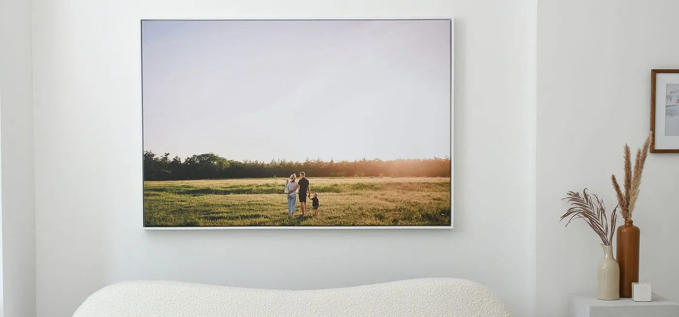 Large framed canvas print of a family in a field, hanging above a bed