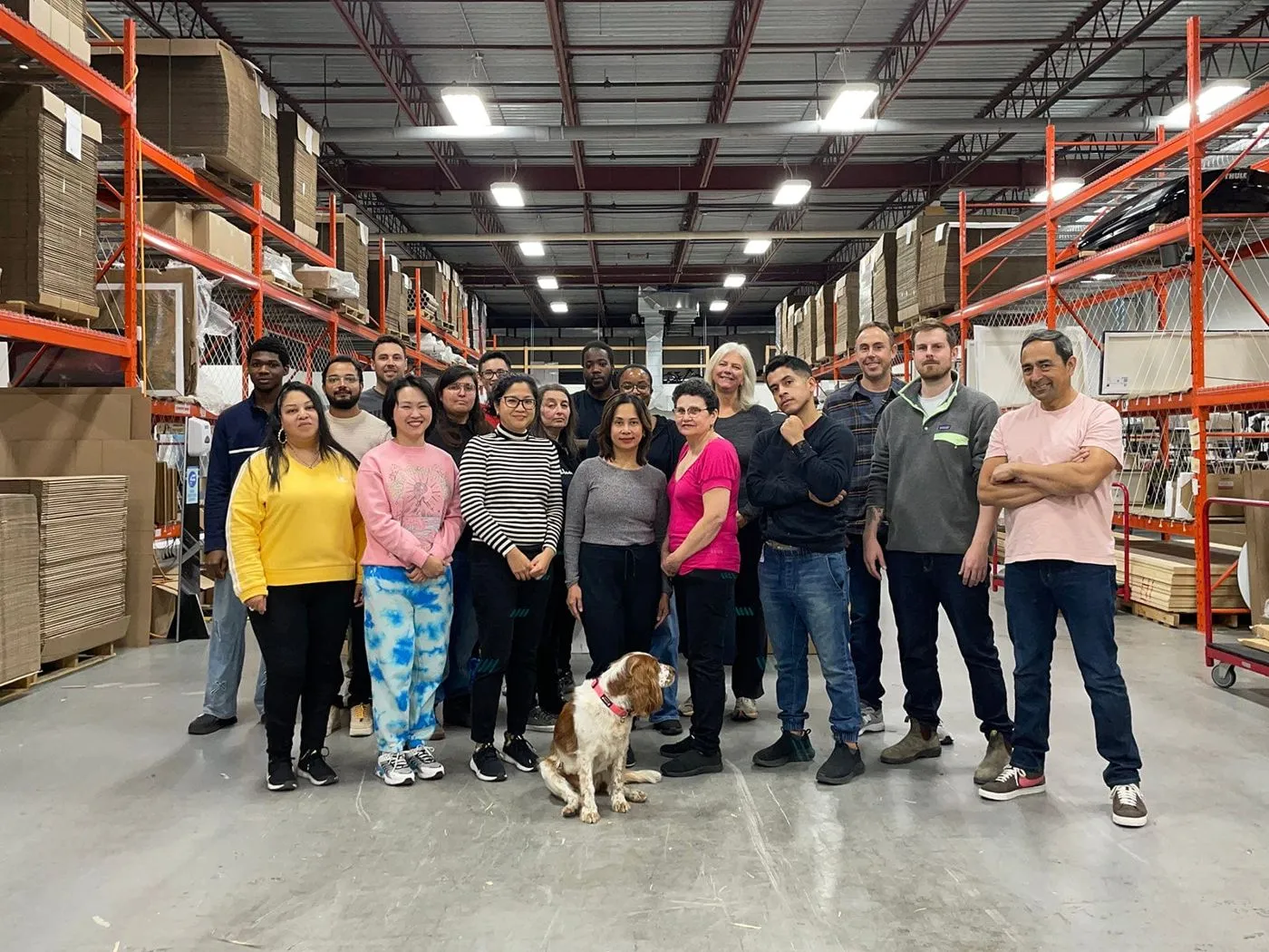 The Posterjack team standing together in their production facility, with a dog in front