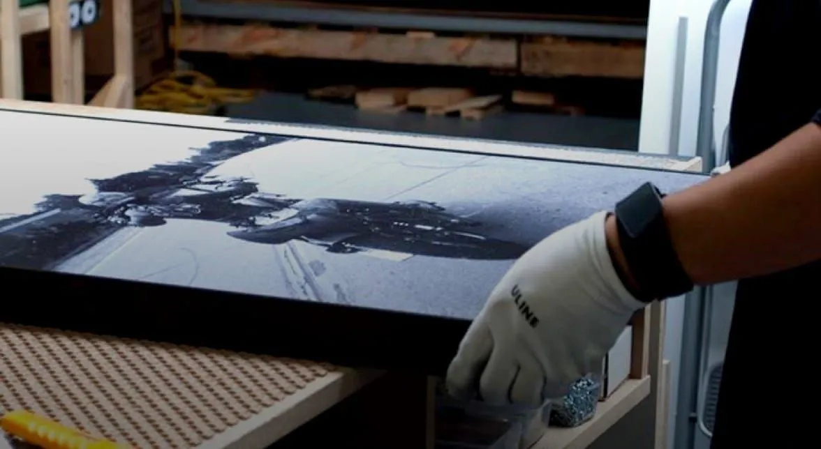Gloved hands finishing a large photo print in a print workshop